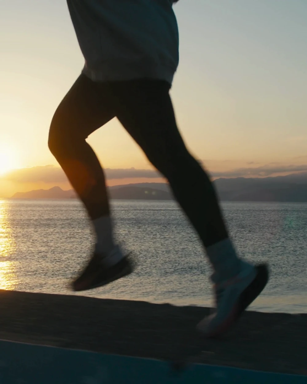 Endurance athlete running at sunrise along a coastal road