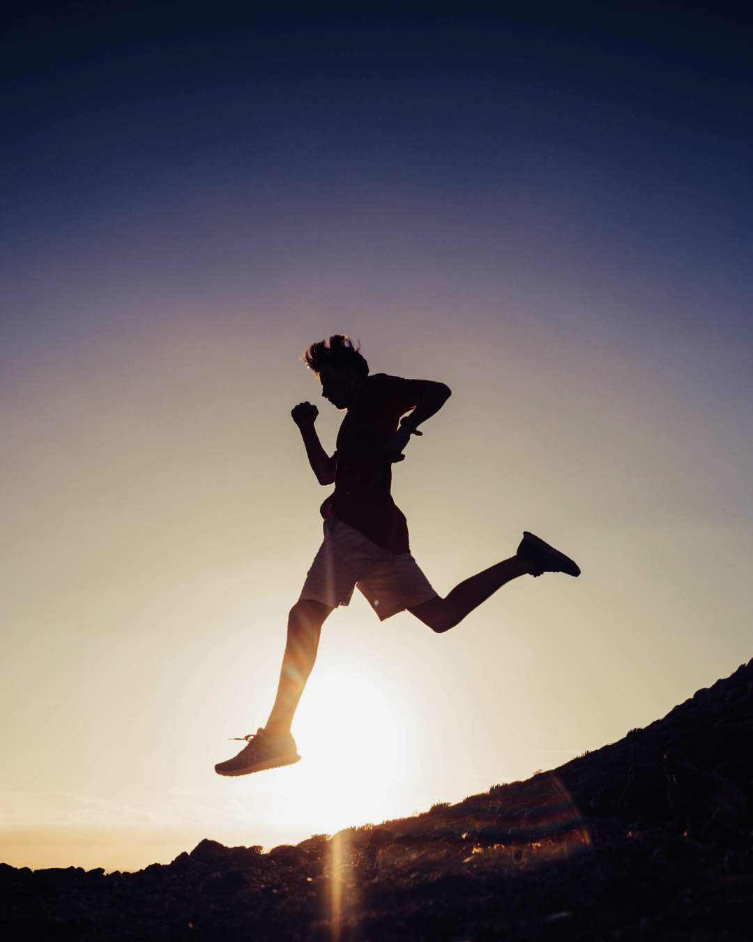 Runner leaping at sunrise, silhouetted against the sun