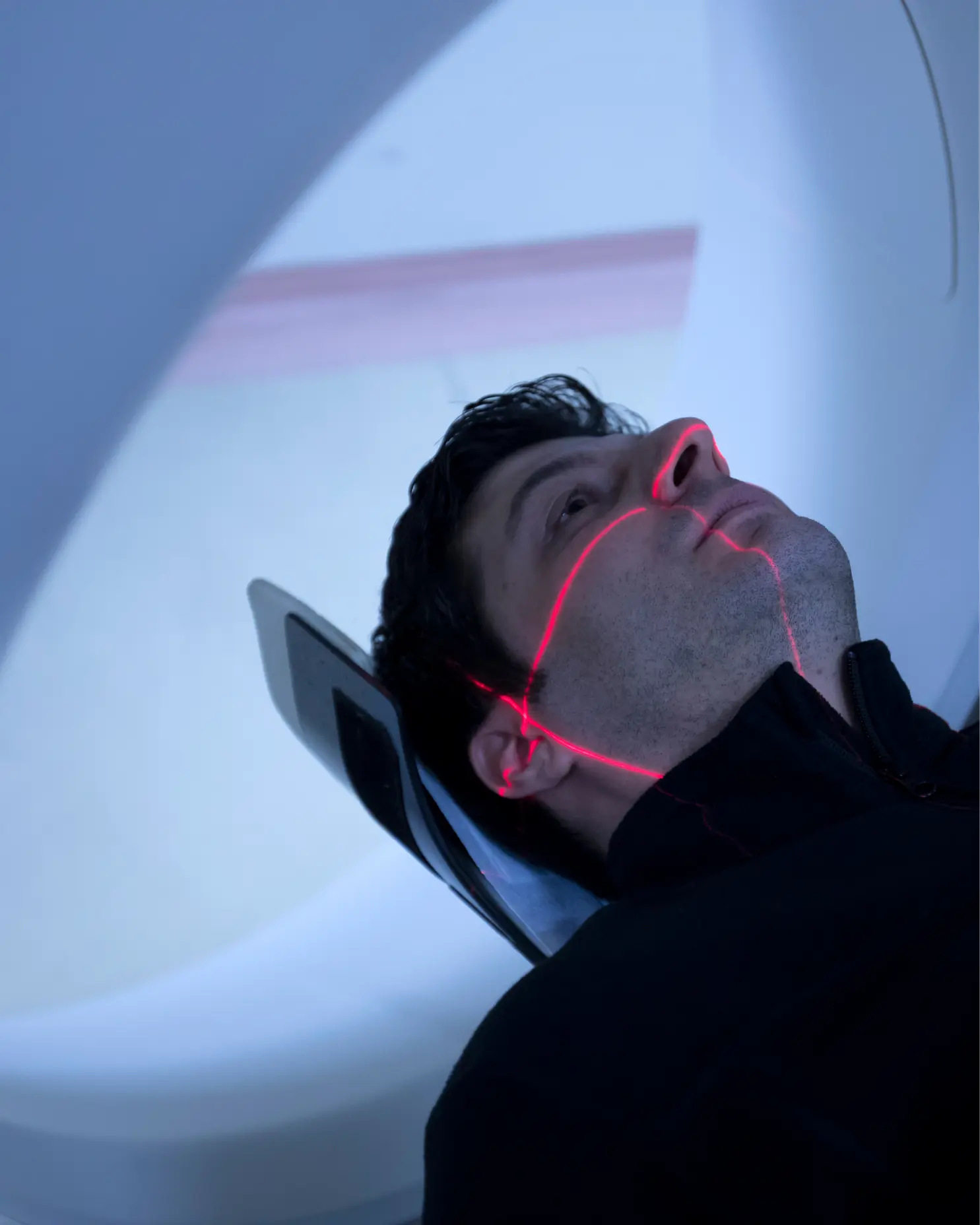 Patient positioned in an MRI scanner with a red laser alignment crosshair